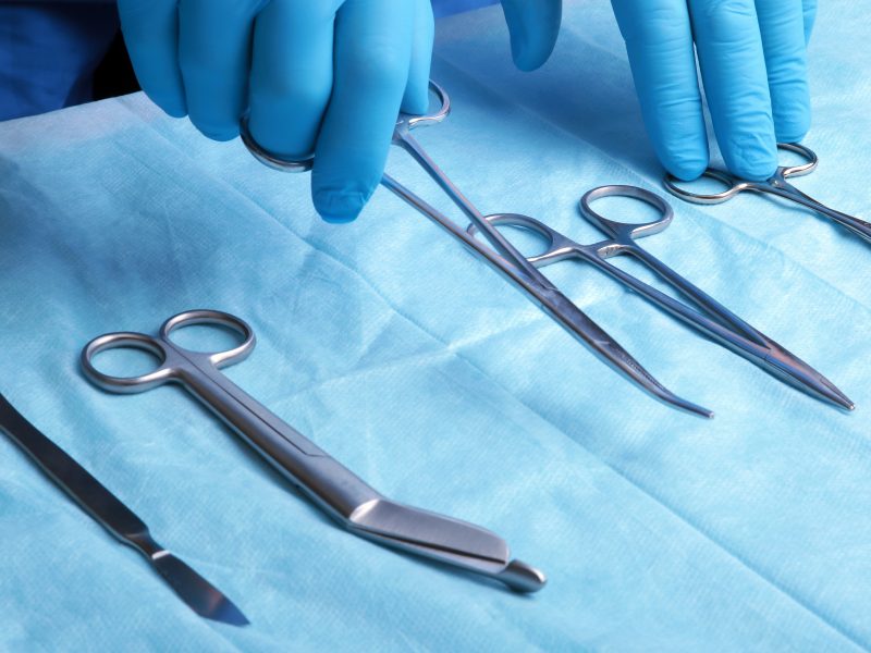 Detail shot of sterilized surgery instruments with a hand grabbing a tool